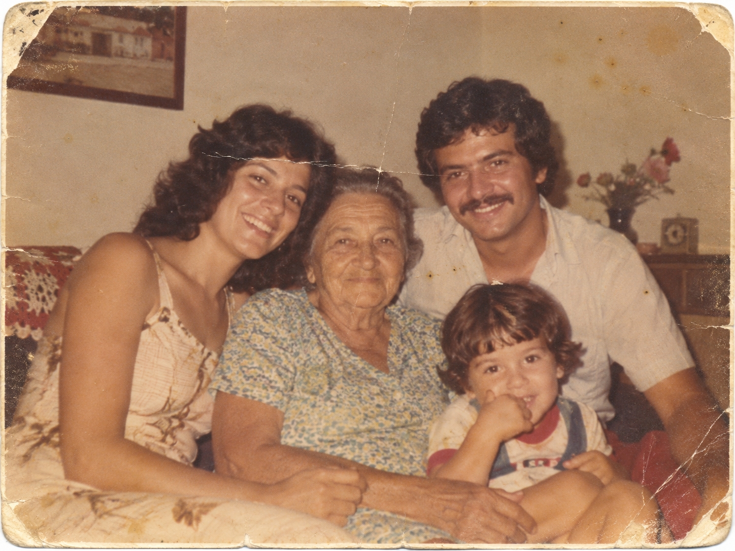 Fotografia antiga de família em tons amarelados, com vincos, rasgos nas bordas e marcas do tempo.